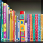 Bookshelf showing multiple spines of children's books with 5 blocks that spell learn.