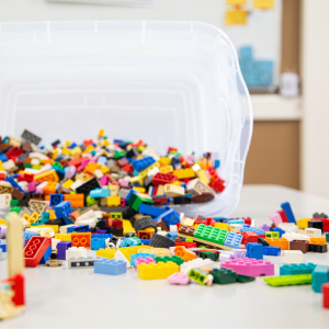 Colourful Lego bricks spilling on a white table from a clear bin.