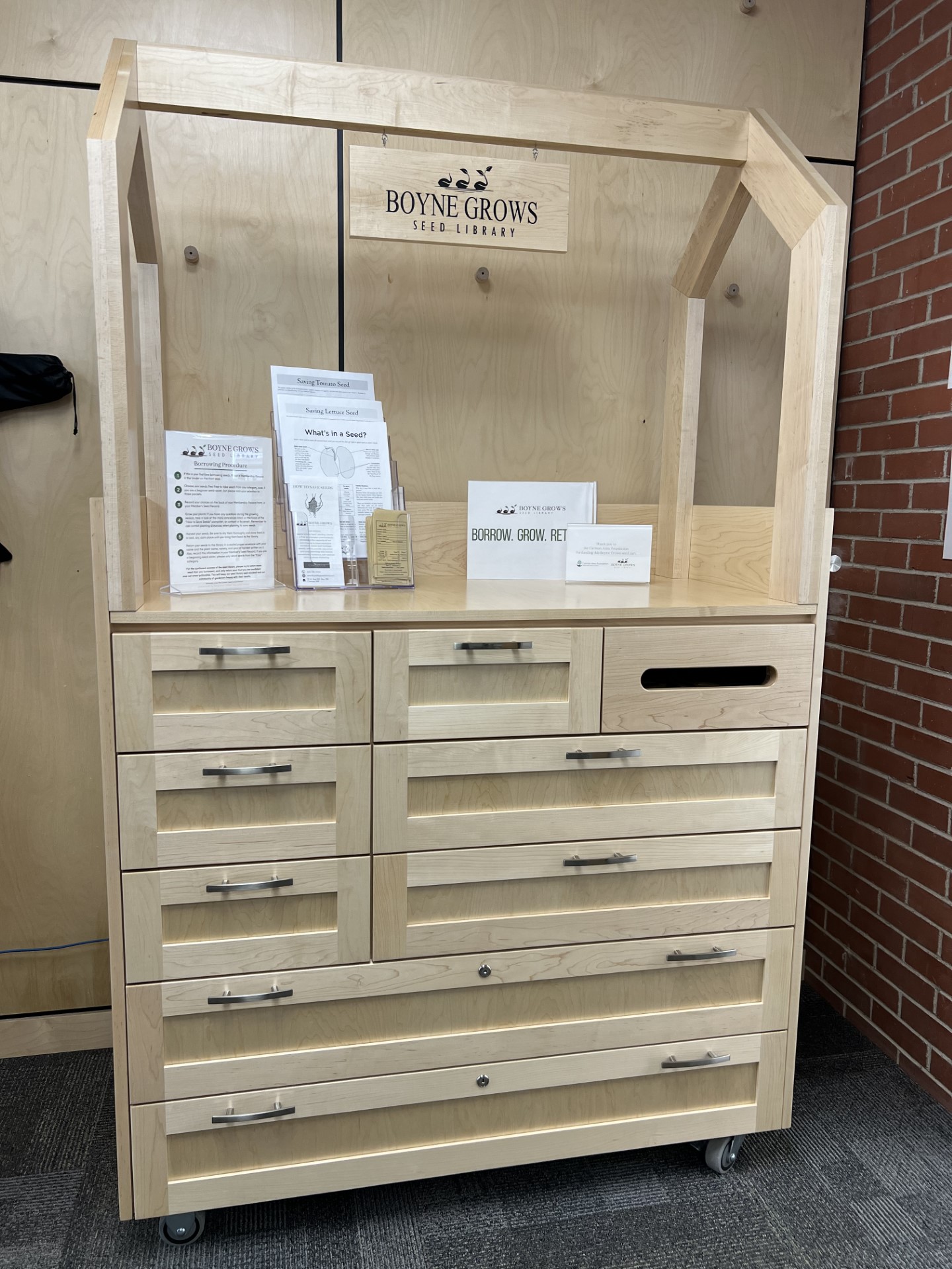 Seed library cart made of wood in a natural finish with multiple drawers to store seeds.
