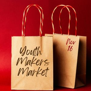 Two kraft paper bags sit in front of a red backdrop with Youth Makers Market Novemeber 16 written on the front.