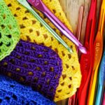 Brightly coloured crocheted squares with crochet hooks.