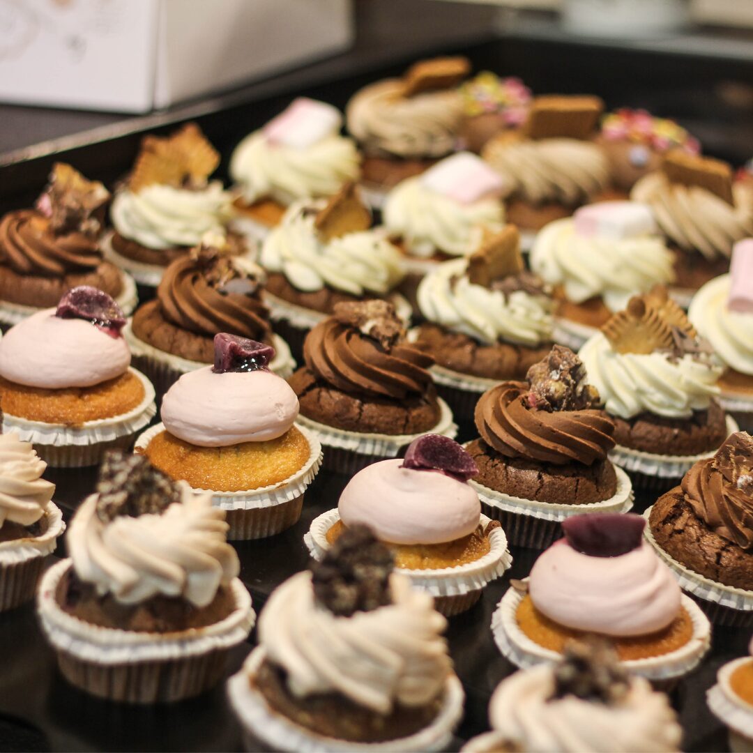 Beautifully decorated and iced cupcakes in rows.