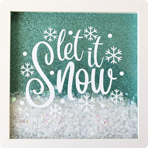 A white framed shadowbox with the words "Let it snow" written in white. The shadow box has a teal sparkly bachground and is filled with snowflakes looking materials.