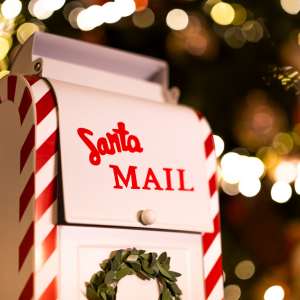 White metal mailbox with red stripes and Santa Mail written on it.