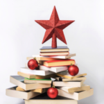 Hardcover books over top of each other in the shape of a triangle like an evergreen tree with a red star on top.